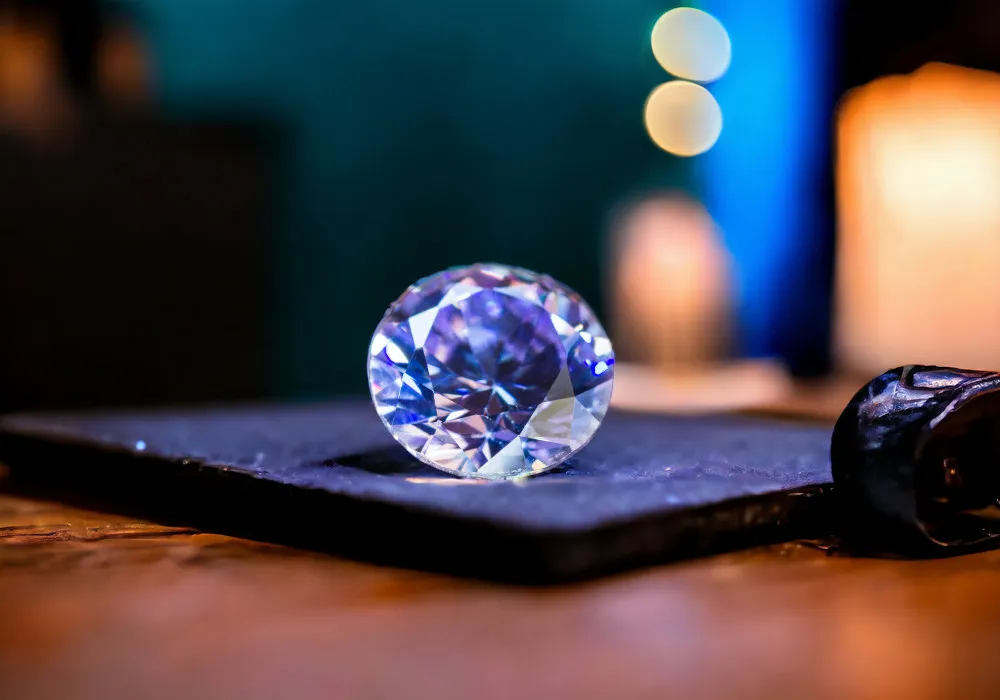 A Tanzanite stone sits on a table next to a candle.