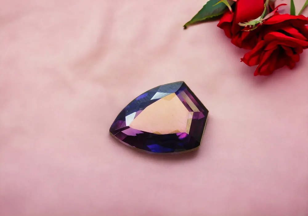 A purple Tanzanite Stone sits on top of a red rose.