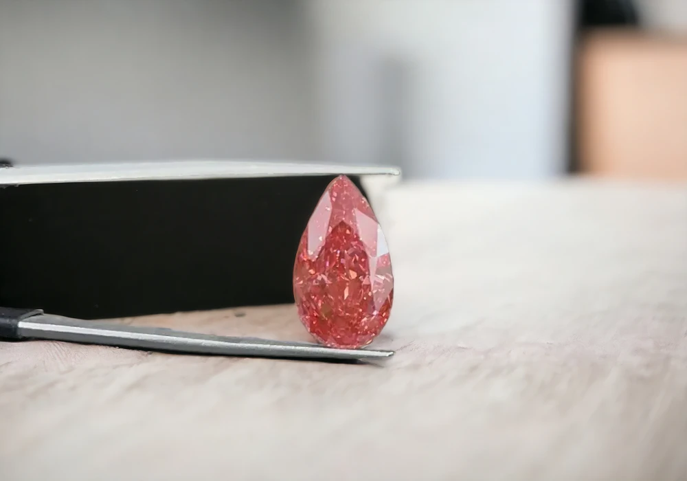 A pink diamond, a stunning example of one of nature's rarest pink gemstones, is delicately placed atop a table.