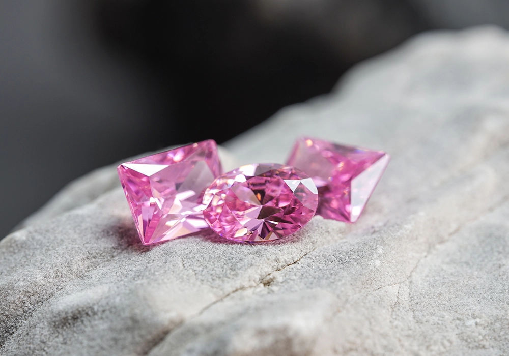 Two pink sapphires on a rock, showcasing stunning pink gemstones.