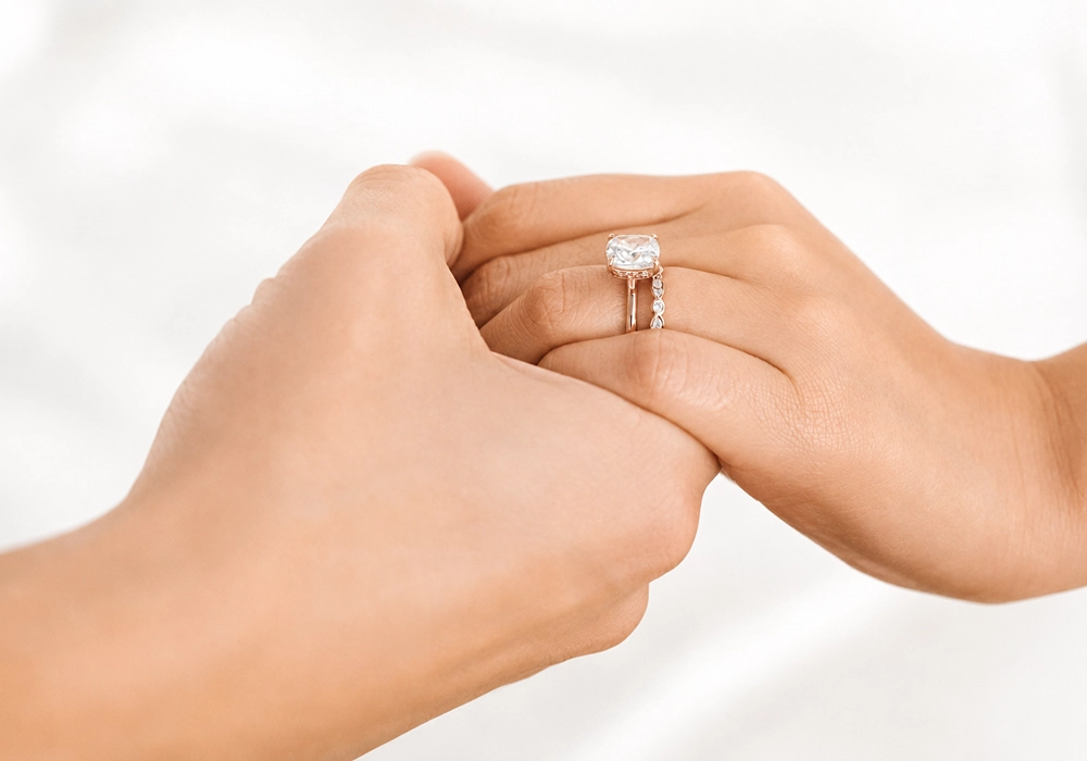 Two hands holding each other, showcasing an elegant engagement ring.
