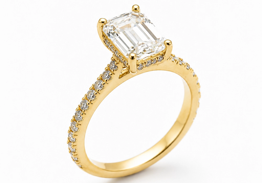 A gold ring with a rectangular emerald-cut diamond center stone and small round diamonds set along the band—a timeless addition to any Diamond Engagement Rings collection.